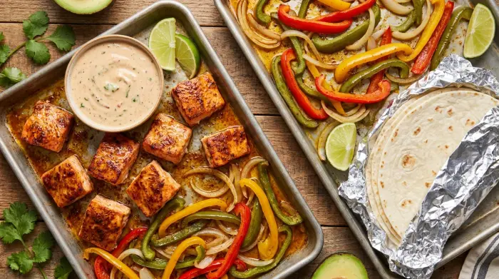 A vibrant spread of baked salmon fajitas with colorful vegetables and toppings on a table.